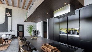Une cuisine moderne dotée d’un grand îlot central, de meubles de couleur noire et offrant une vue sur l’extérieur.
