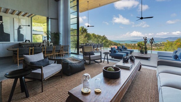 Un salon moderne doté d’un grand mur de verre, aménagé avec des canapés, des fauteuils et une table basse.