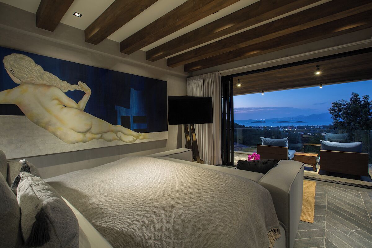 A bedroom with a large bed, a painting, a TV, and a balcony with a view.