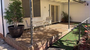 A covered patio area with a seating arrangement, a potted plant, and a number '68' on the wall.