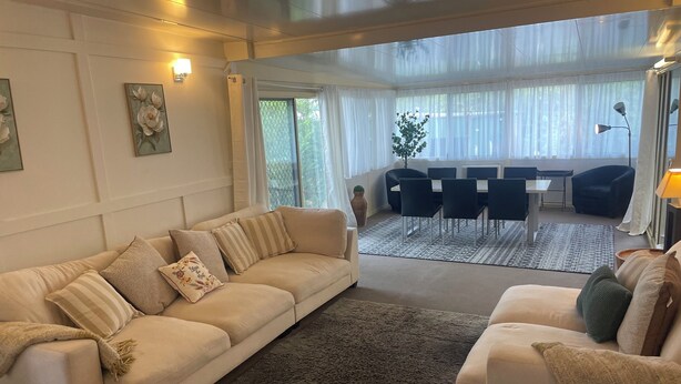 A modern living room with a beige sofa, a coffee table, and a dining area with a table and chairs.