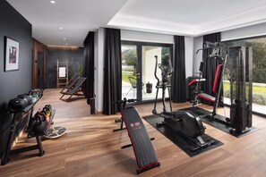 A modern gym with exercise equipment, a bench, and a view of greenery outside. - Villa Valmata Adriatic Pearl /w Pool & Wellness (Rasa)
