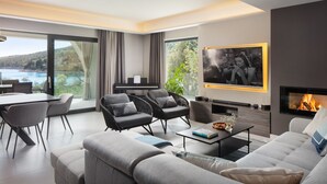 A modern living room with a fireplace, a dining area, and a view of the sea. - Villa Valmata Adriatic Pearl /w Pool & Wellness (Rasa)