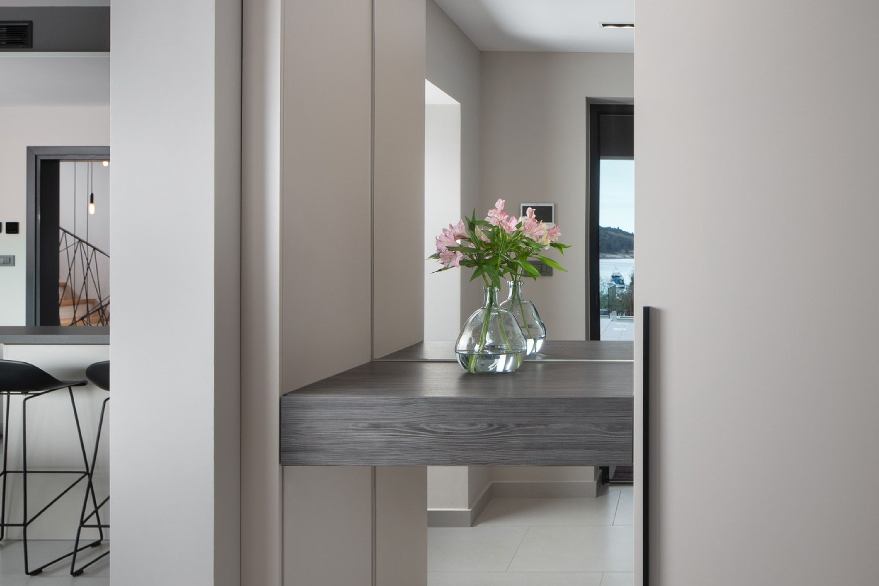 Una cocina moderna con encimera de madera oscura, un florero con flores y vistas al exterior a través de un amplio ventanal.