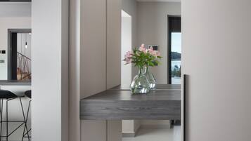 Una cocina moderna con encimera de madera oscura, un florero con flores y vistas al exterior a través de un amplio ventanal.