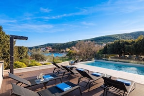 A poolside area with lounge chairs and a view of a lake and hills. - Villa Valmata Adriatic Pearl /w Pool & Wellness (Rasa)
