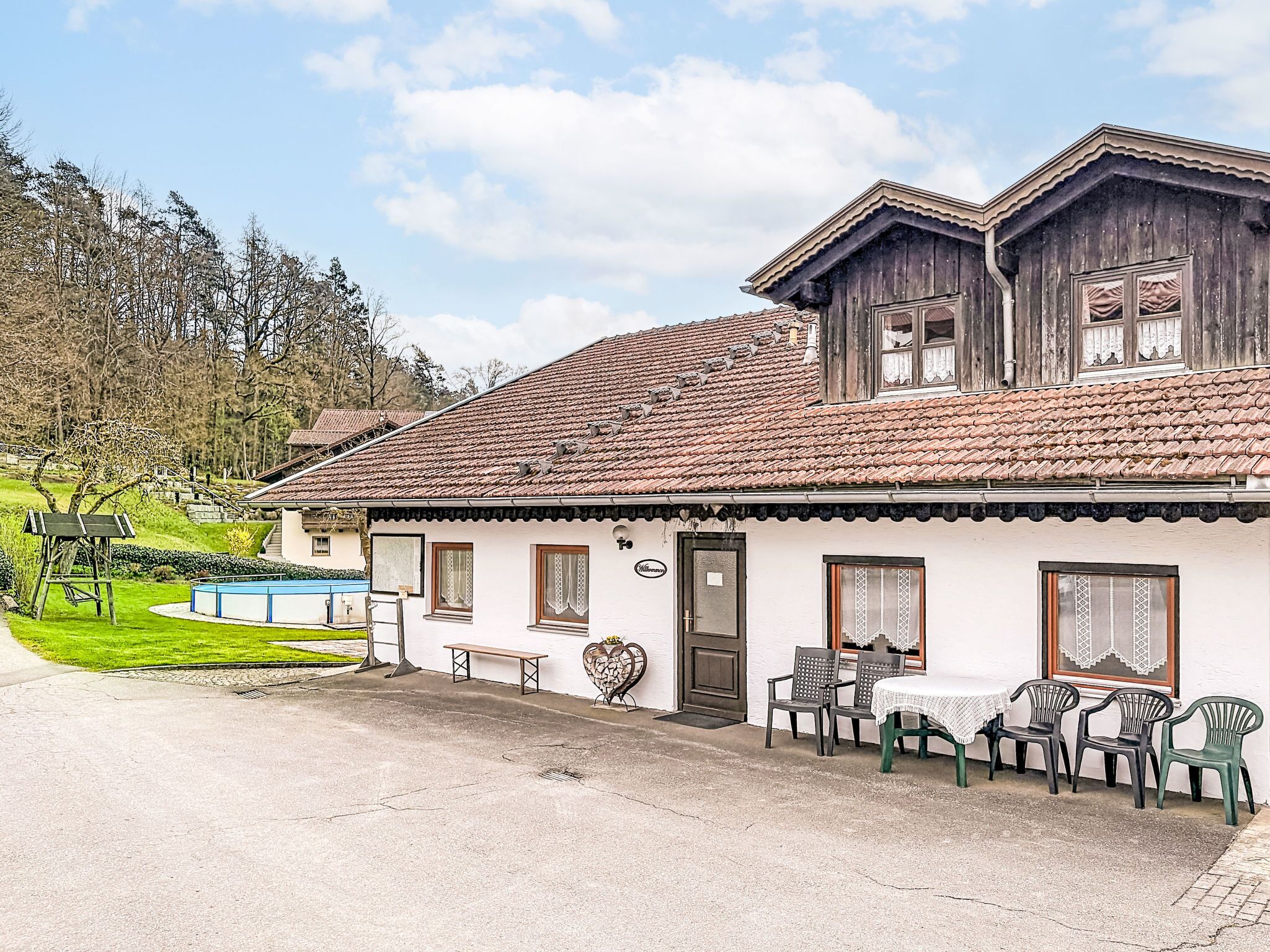 A traditional chalet with a tiled roof, a swimming pool, and outdoor seating.