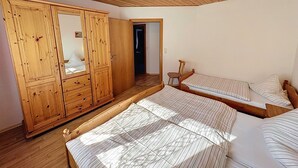 A room with wooden furniture, including a wardrobe and a bed with striped bedding. - Ferienhof Wolf by Interhome (Viechtach)