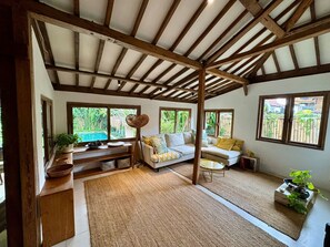 Ein Zimmer mit Holzboden, einer Couch, einem kleinen Tisch und Blick auf Grün.