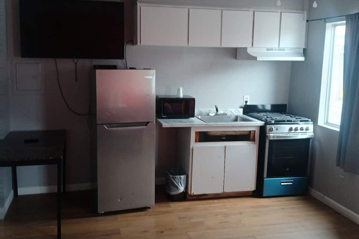 A compact kitchen with a refrigerator, microwave, stove, and ceiling fan.