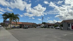 Un motel con techo rojo, coches aparcados y cielo despejado.