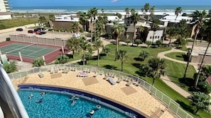 A pool area with a tennis court, palm trees, and a view of the ocean. - 3rd Coast Getaways - Sunchase IV 330 (South Padre Island)