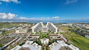 A modern hotel with a central courtyard, multiple floors, and a view of the ocean. - 3rd Coast Getaways - Sunchase IV 330 (South Padre Island)