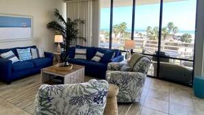 A living room with a blue sofa, a patterned armchair, and a coffee table. - 3rd Coast Getaways - Sunchase IV 330 (South Padre Island)