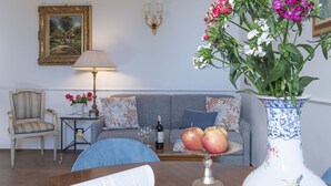Una sala de estar con un sofá, una silla, una mesa con un florero y una lámpara.