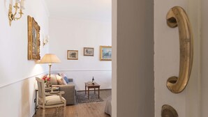 Una habitación con un sofá, una silla, una mesita con botellas y cuadros colgados en la pared.