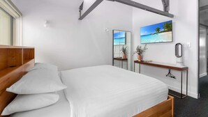 A modern hotel room with a bed, a bedside table, a mirror, and a wall-mounted TV. - Spacious 2-Bed Retreat in Rosebery (Rosebery)