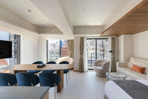 Ein modernes Hotelzimmer mit Essbereich, einer Couch, einem Bett und Blick auf die Stadtlandschaft.