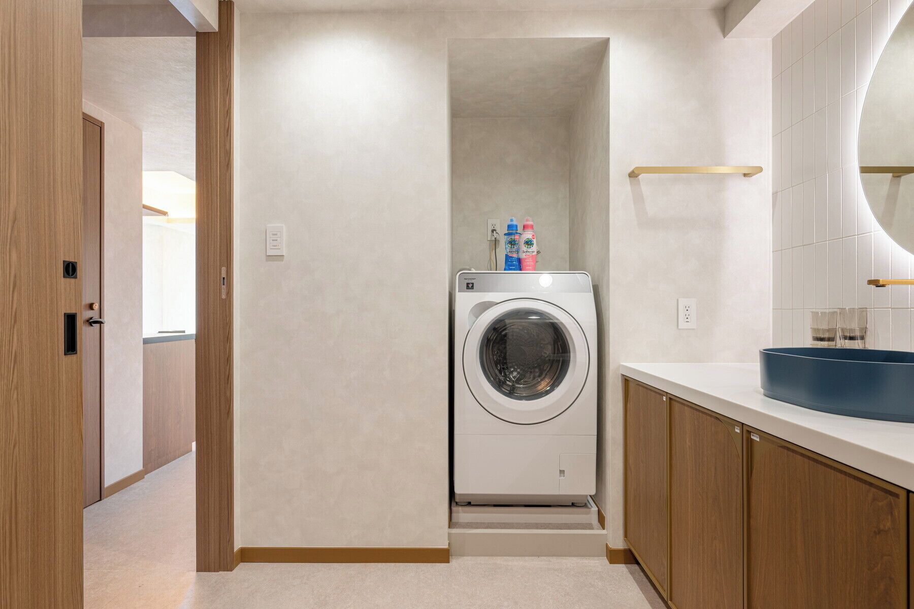 A laundry room with a washing machine, a sink, and a mirror.