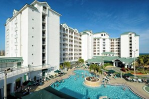 Ein Hotel mit mehreren weißen Gebäuden, einem zentral gelegenen Schwimmbad und Sitzbereichen im Freien.