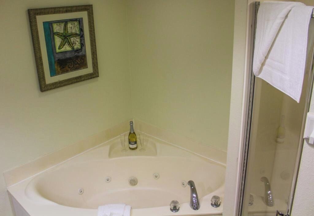 Une salle de bain avec une baignoire, une douche et une œuvre d’art encadrée au mur.