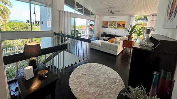 A spacious living area with a white sofa, a round rug, and a balcony with a view.