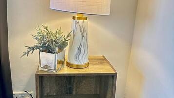 Une table de chevet avec une lampe, une petite plante et un vase décoratif.