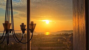 A sunset view through a window with a chandelier.
