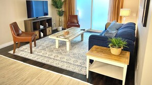 A living room with a sofa, armchair, coffee table, TV, and a sliding glass door. - Spacious 2 BR Suite, Family Friendly, near Colwood Waterfront, Royal Roads Univ (Victoria)