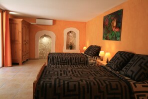 A bedroom with two beds, a stone wall, and a painting. - Gite lafontaine Puisserguier, between garrigue and sea (Puisserguier)