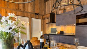 Interior de madeira com uma mesa de jantar posta para dois, um vaso de flores e uma garrafa de vinho Castiglione.
