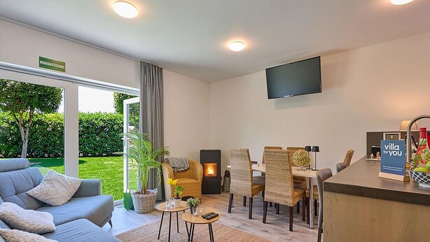 Ein modernes Hotelzimmer mit einer Couch, einem Esstisch, Stühlen, einem Fernseher und einem Schild mit der Aufschrift 'villa for you'.