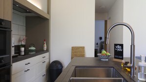 Eine moderne Küche mit Spüle aus Edelstahl, weißen Schränken und einer Obstschale auf der Arbeitsfläche.