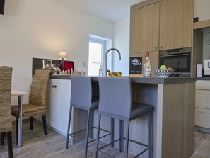 A modern kitchen with a central island, bar stools, a chessboard, and a 'villa for you' sign.