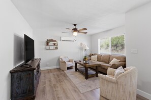 Ein Wohnzimmer mit Flachbildfernseher, Deckenventilator, Sofa, Couchtisch und Holzschrank.