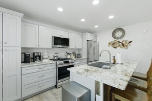 A modern kitchen with white cabinetry, stainless steel appliances, a marble countertop, and a built-in oven. - 2BR Home Near Prescott Square - Gray Frontier House (Prescott)