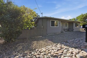 A single-story house with a gravel driveway and a wooden fence. - 2BR Home Near Prescott Square - Gray Frontier House (Prescott)
