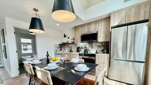 A modern kitchen with a dining area, stainless steel appliances, and a flat-screen TV. - RETRORIDGE - DOWNTOWN - ROOFTOP HOT TUB (Canmore)