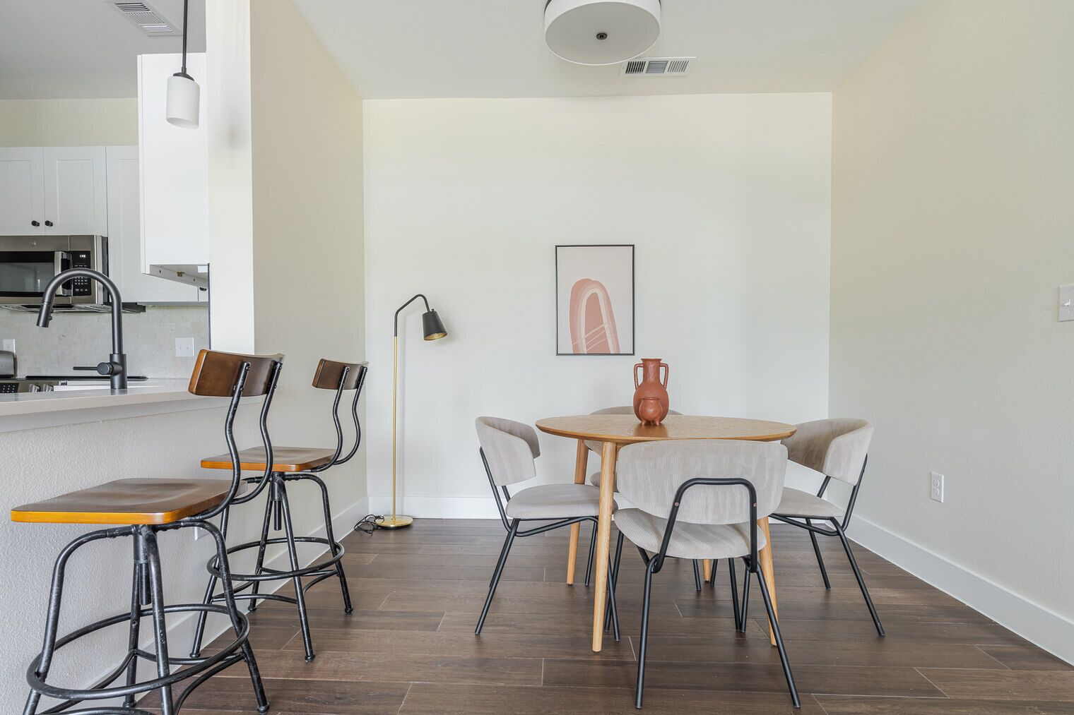 A modern kitchen with white cabinets, a stainless steel range hood, and a built-in microwave.