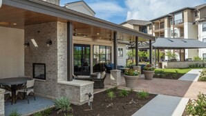 A covered outdoor patio with seating, a fire pit, and potted plants. - Blueground | Scofield Farms, pool, nr Walnut Creek Park (Austin)
