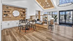 A spacious living room with a high ceiling, wooden beams, and a large window offering a view of the outdoors. - Blueground | Scofield Farms, pool, nr Walnut Creek Park (Austin)