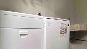 A white appliance, possibly a washer or dryer, with a control panel and a sticker on the side.