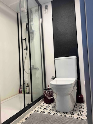 A bathroom with a glass-enclosed shower, a toilet, and a tiled floor. - Tinyweeny House 15min to Ist Airport (Eyup)