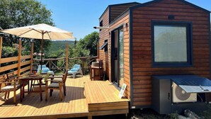 A wooden deck with outdoor furniture, a small building with a large window, and a view of the surrounding landscape. - Tinyweeny House 15min to Ist Airport (Eyup)