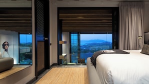 A modern hotel room with a large bed, a seating area, a view of the outdoors, and a sliding door leading to a balcony. - Villa Sierra (Koh Samui)