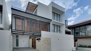 A modern multi-story building with a flat roof, large windows, and a stone wall entrance. - Villa RHYS - Canggu (Canggu)