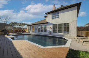 Ein Haus mit Swimmingpool, überdachter Terrasse und umzäunter Garten.