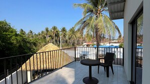 A balcony with a table and chairs, a metal railing, and a view of palm trees and a building in the background. - Just 5-minutes away to the beach. Spacious 5-bedroom house at Costa Azul,Metalio (Metalio)