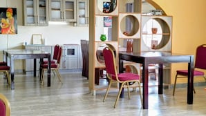 Ein Essbereich mit Holztischen und -stühlen, einem dekorativen Regal mit runden Spiegeln und einem Gemälde an der Wand.