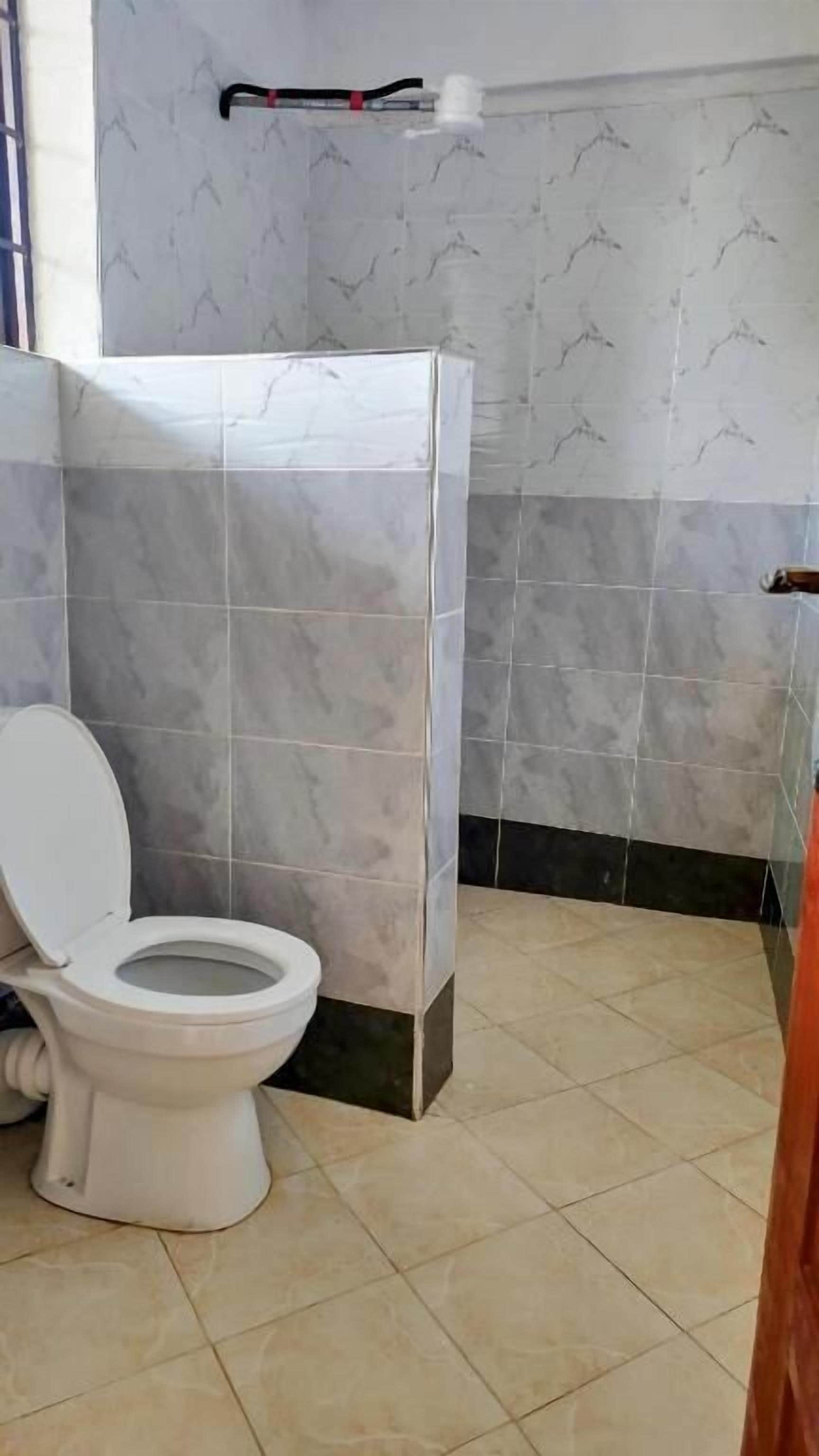 Ein Badezimmer mit Toilette, Duschkabine und Fliesenwänden.